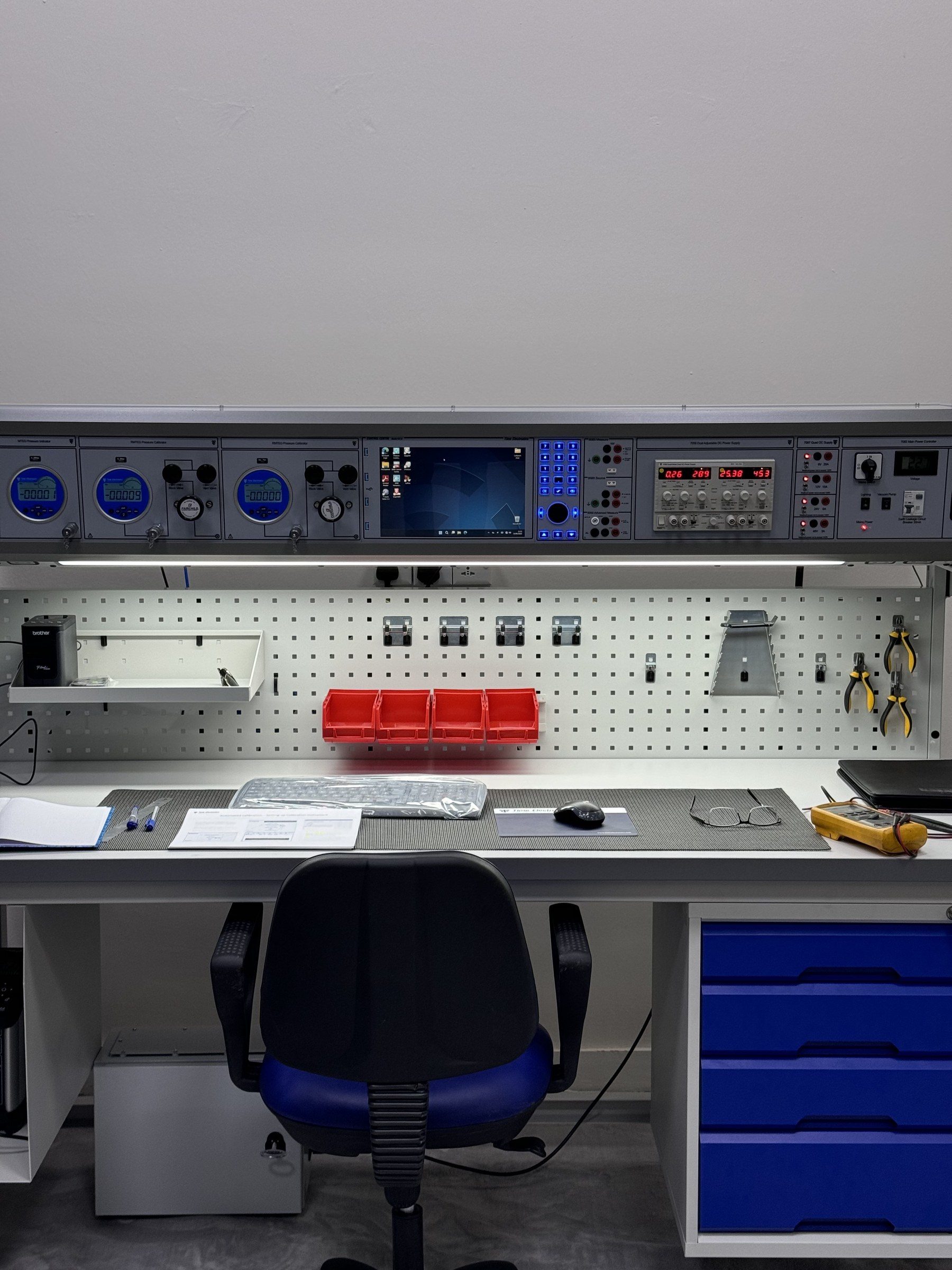 The instrument panel of a calibration bench, above a pegboard of tools.
