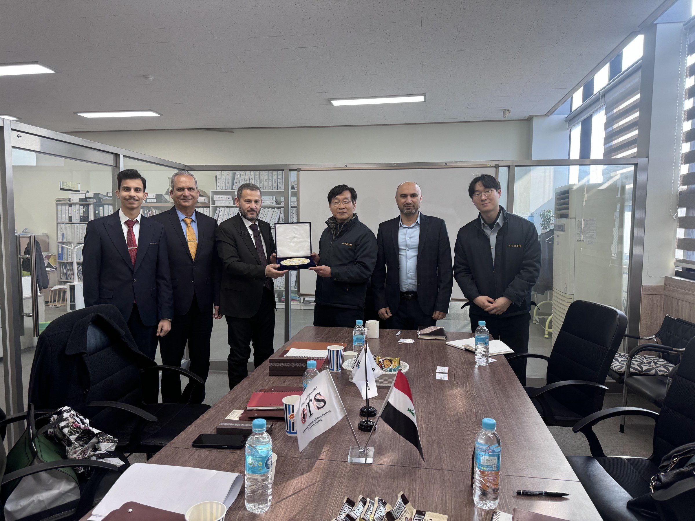 The delegation presents a plaque to Seoul Tech's management in the meeting room.